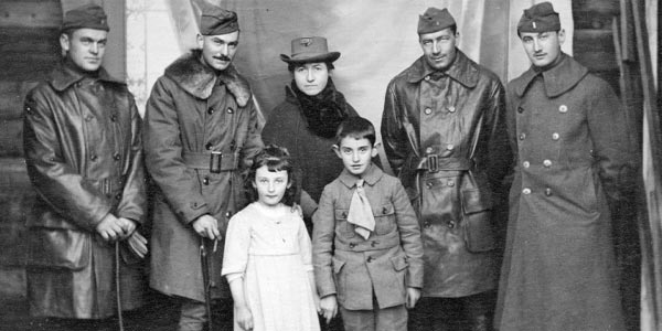 Men in uniform posing with a woman and two small children.