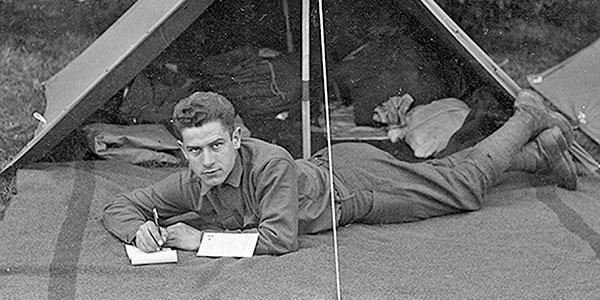 photo of a soldier in front of a tent writing
