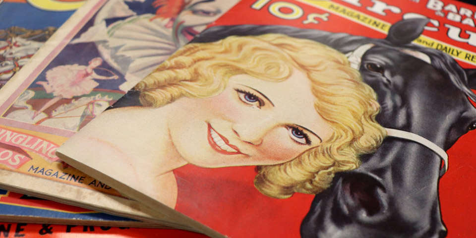 Stack of circus magazines and programs featuring illustrations of circus performers and animals
