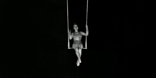 black and white photo of a woman sitting on a trapese.