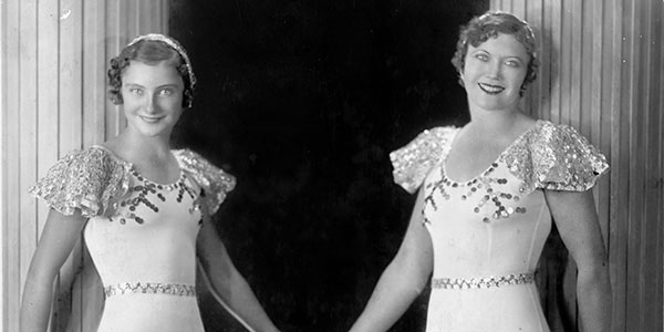 photo of two women in circus costumes holding hands