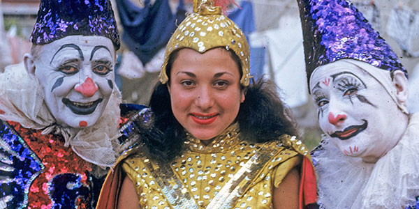 photo of a woman in circus costume flanked on either side by clowns