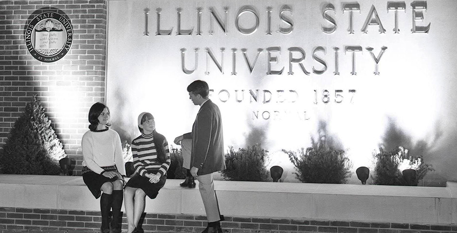 Three people in front of a brick and concrete wall with the ISU seal and 'Illinois State University - Founded 1857 - Normal'