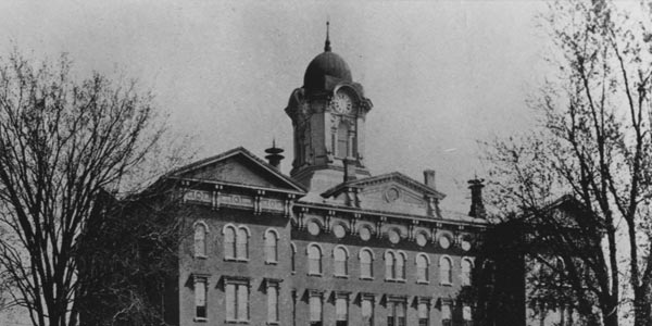 Black and white photograph of Old Main, the original building on the campus of Illinois State Normal University, in 1907.  The photograph was taken from the southwest and shows the front of the building.