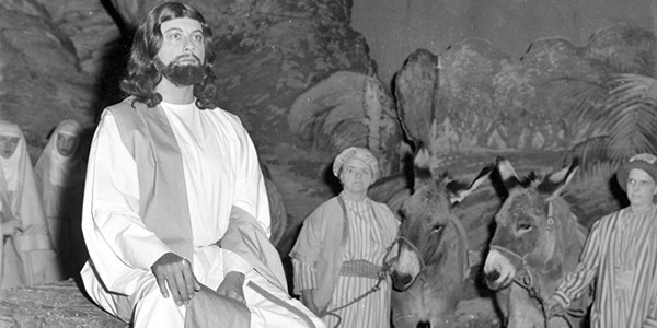 Actor portraying Jesus with donkeys in the background of a Passion Play