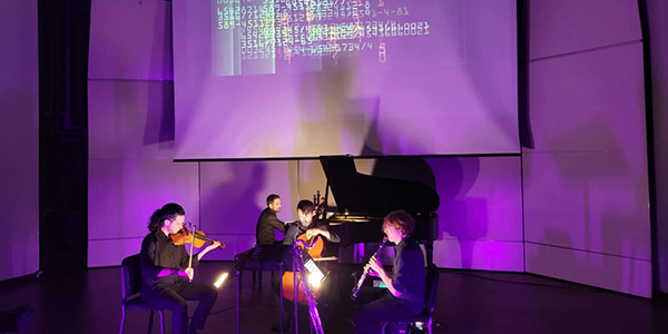 Quartet of musicians playing on a dramatically lit stage 