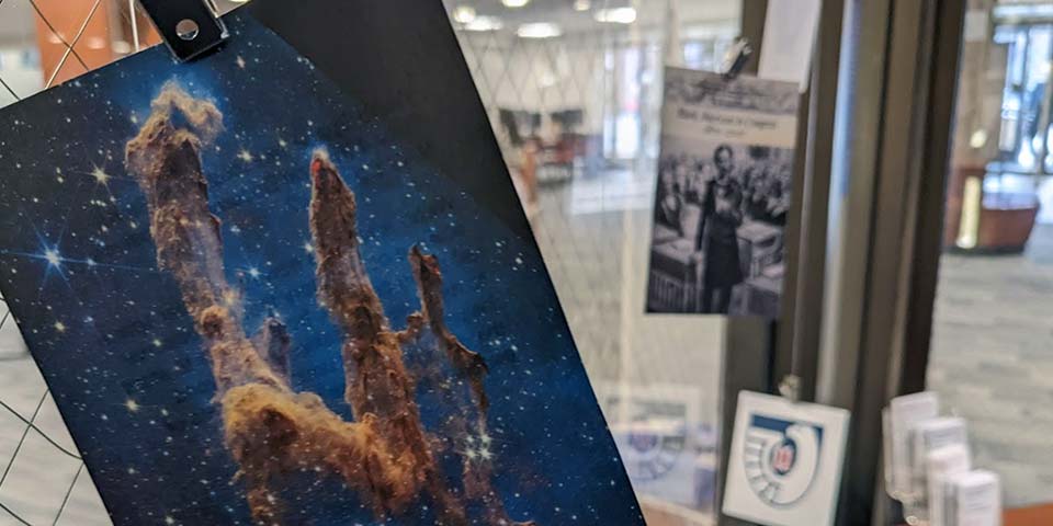 Images of government documents hanging against a glass window, featuring an image of the Pillars of Creation.