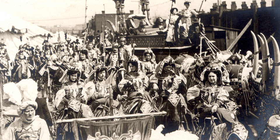 Group of women riding horses in full circus costume.