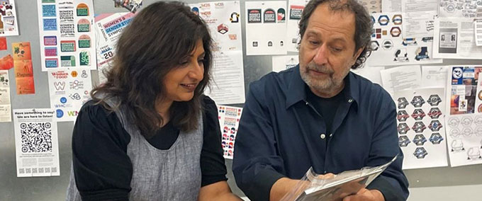 Designer Rick Valicenti shows Professor Archana Shekara one of the more than 100 pieces of design he donated to Illinois State University.